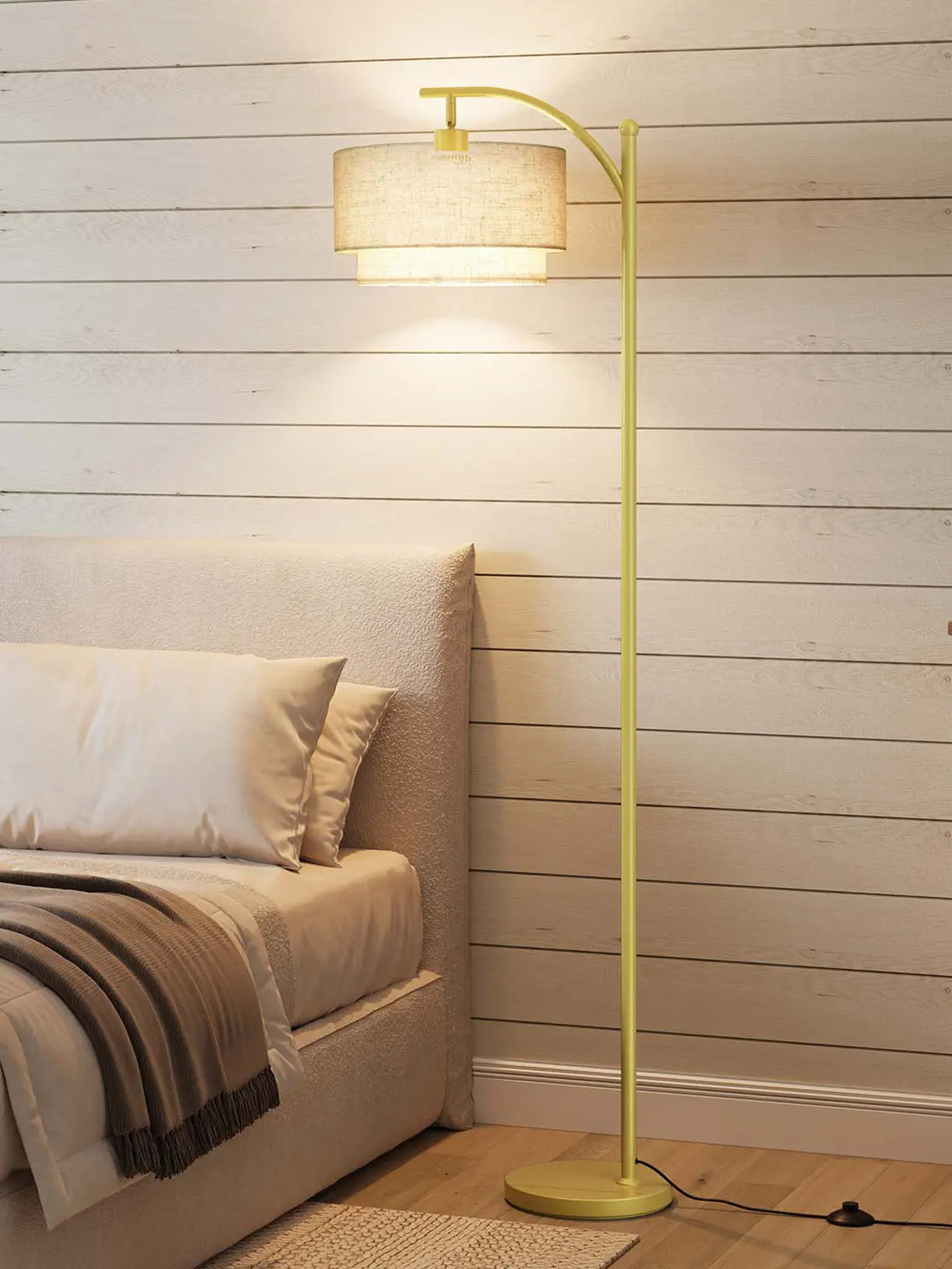 An industrial-style arc floor lamp in a dark metal finish with a bell-shaped shade, extending over a seating area to offer direct task lighting with a rugged aesthetic.