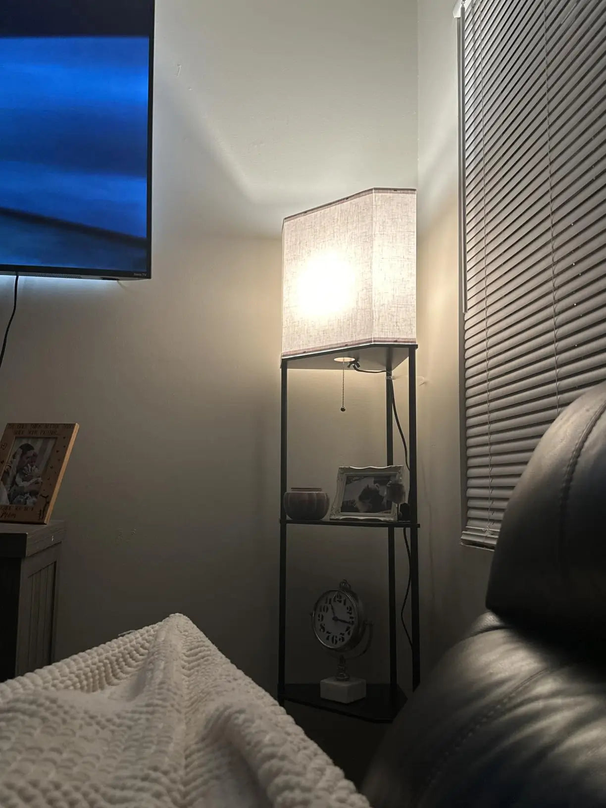 A minimalist corner shelf floor lamp in a light finish, combining a functional lighting source with multiple tiers for displaying decorative items, optimizing corner space.