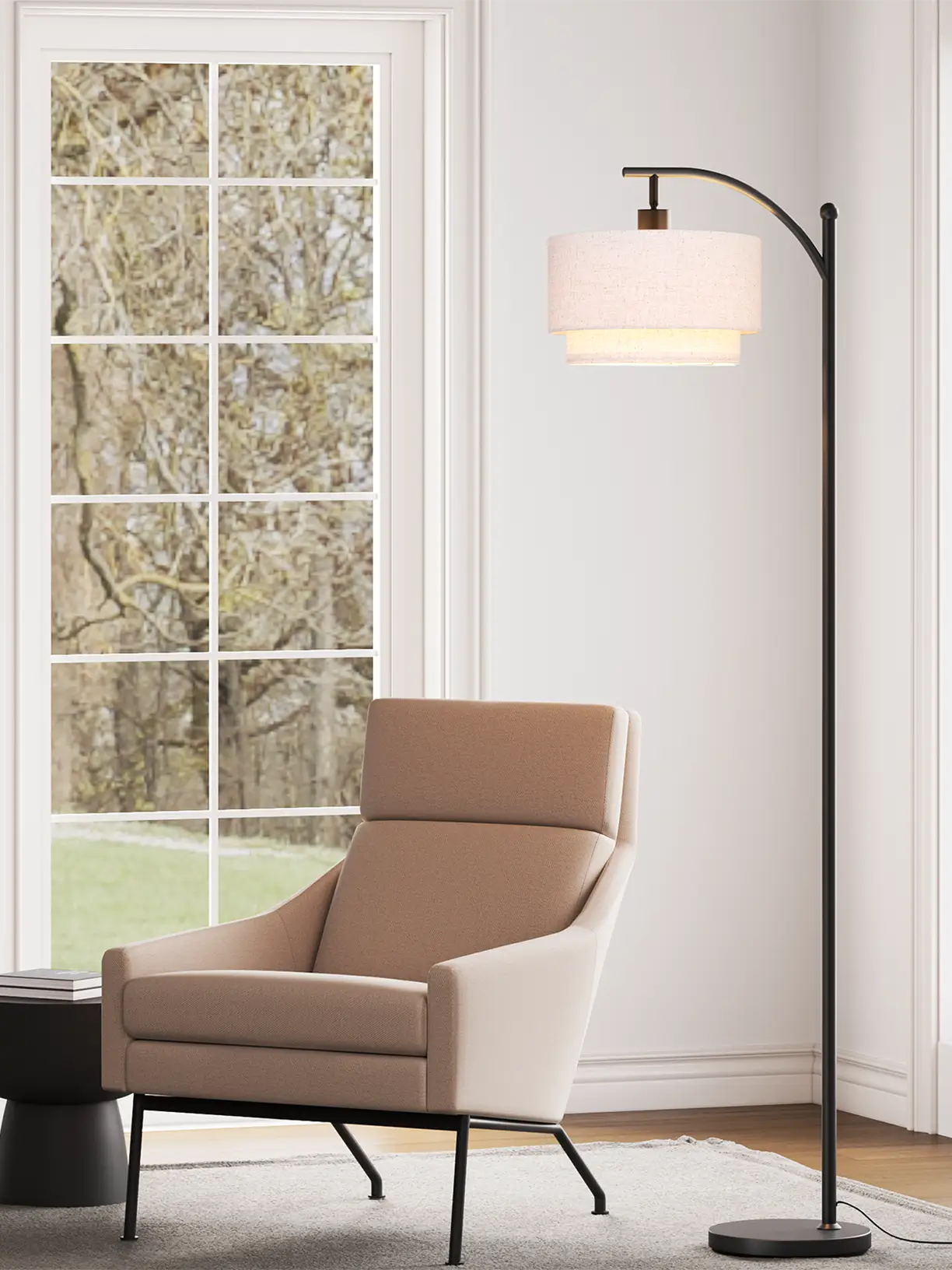 A modern arc floor lamp featuring a large, light-colored fabric drum shade, casting a warm glow over a comfortable armchair and books, ideal for a cozy reading nook.
