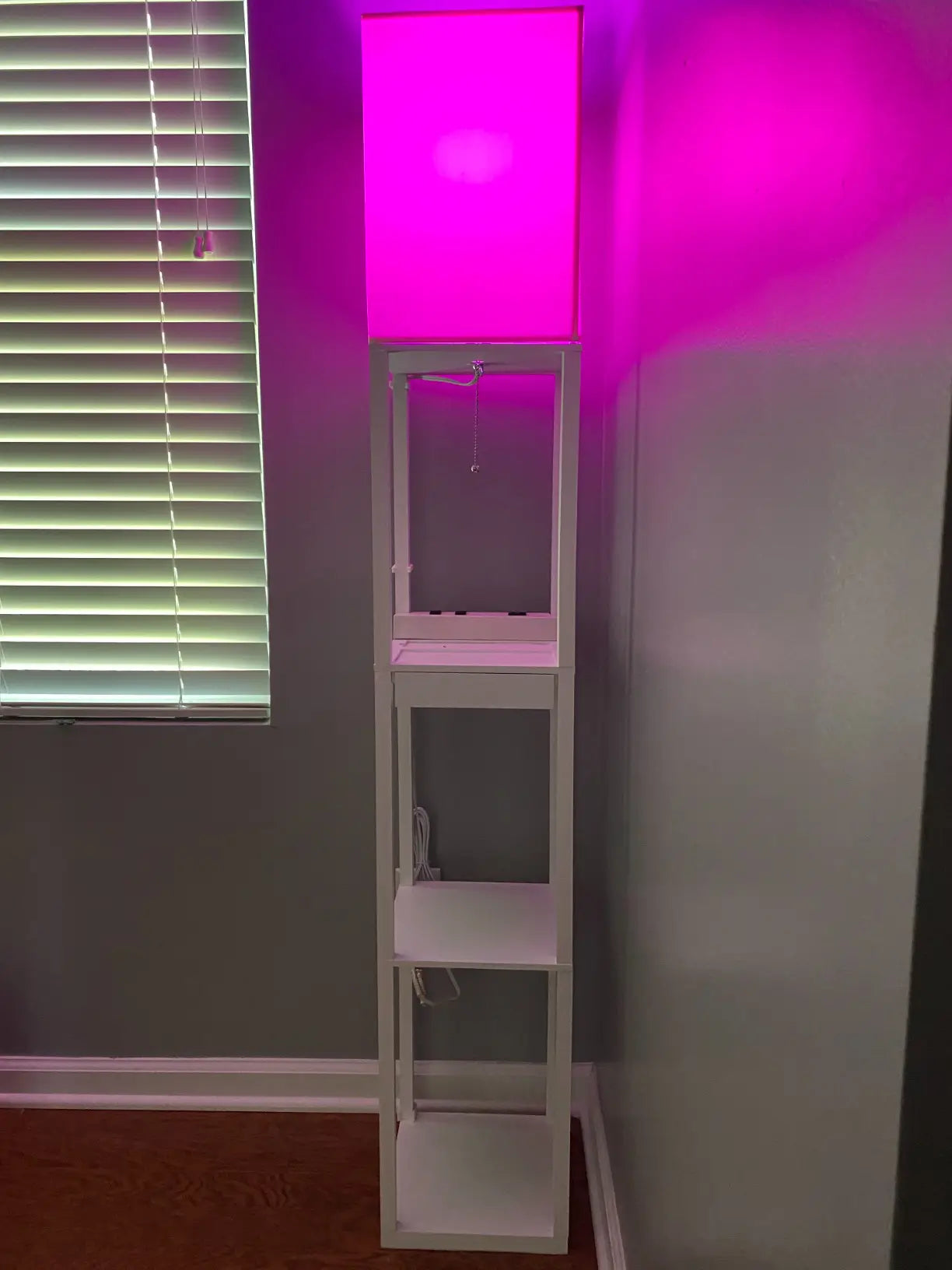 A modern, slender RGB floor lamp projecting colorful light onto a wall, offering smart app control for creating a personalized and vibrant ambiance in any room.
