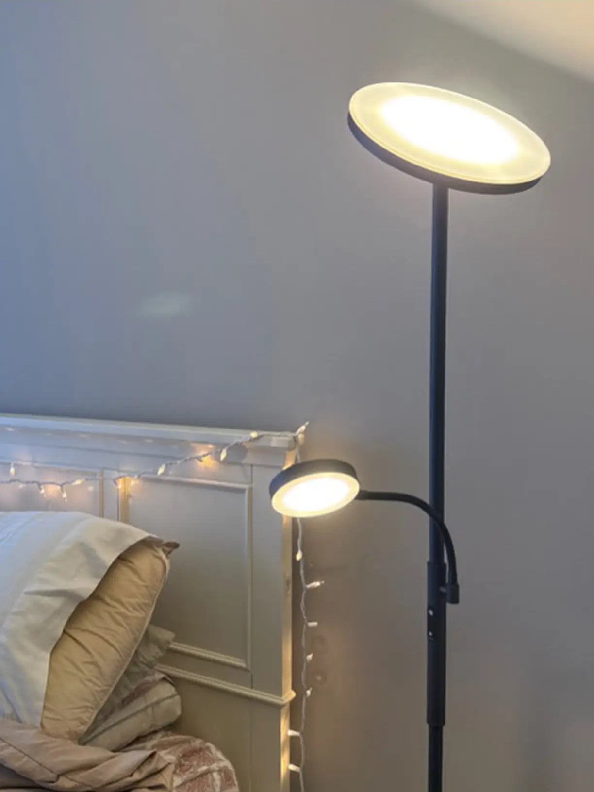 A modern torchiere floor lamp with a white top shade for ambient uplighting and an adjustable side lamp with a white dome shade, perfect for reading in a living room.