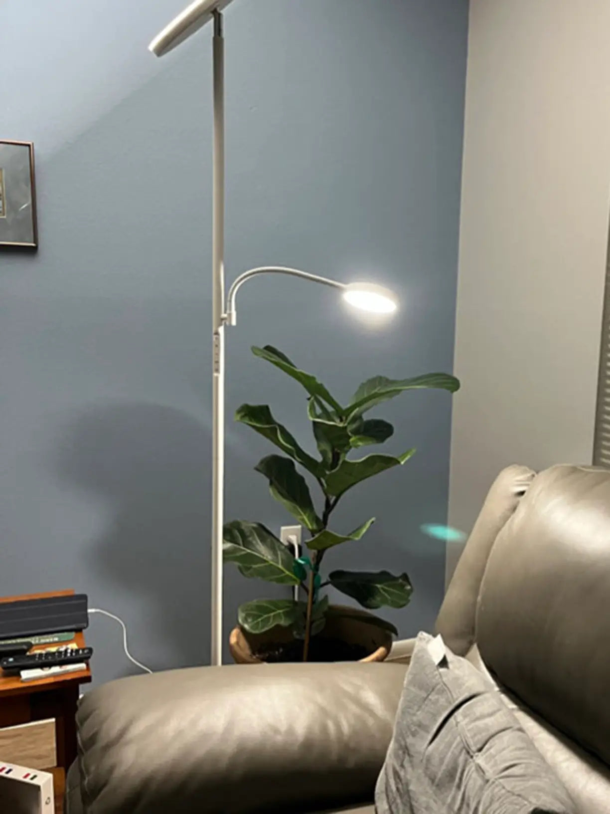 A modern white torchiere floor lamp with an upward-facing light and a flexible, adjustable secondary lamp, offering versatile lighting options for a living room or bedroom, suitable for both ambient and task illumination.