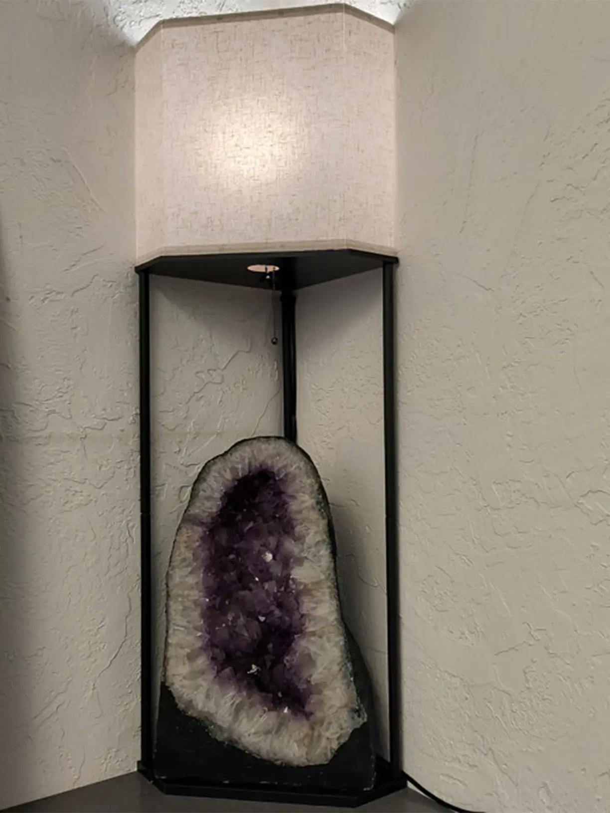A tall corner shelf floor lamp featuring a light fabric shade and multiple open shelves, designed to maximize space and provide ambient light in a cozy corner.