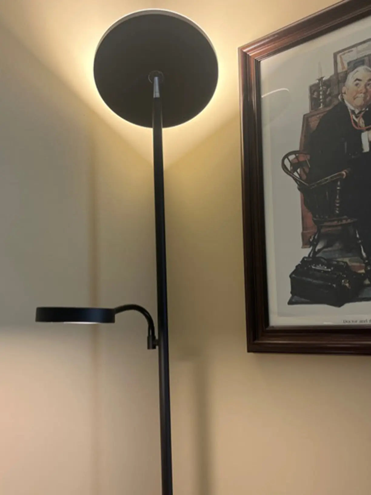 Torchiere floor lamp designed for dual functionality, offering both upward ambient lighting and a flexible, directional task light for reading or hobbies in a comfortable armchair setting.