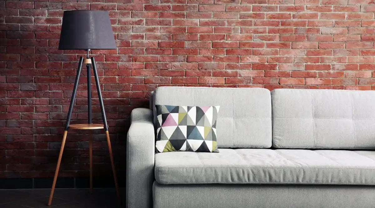 Grey sofa and floor lamp against brick wall in the room