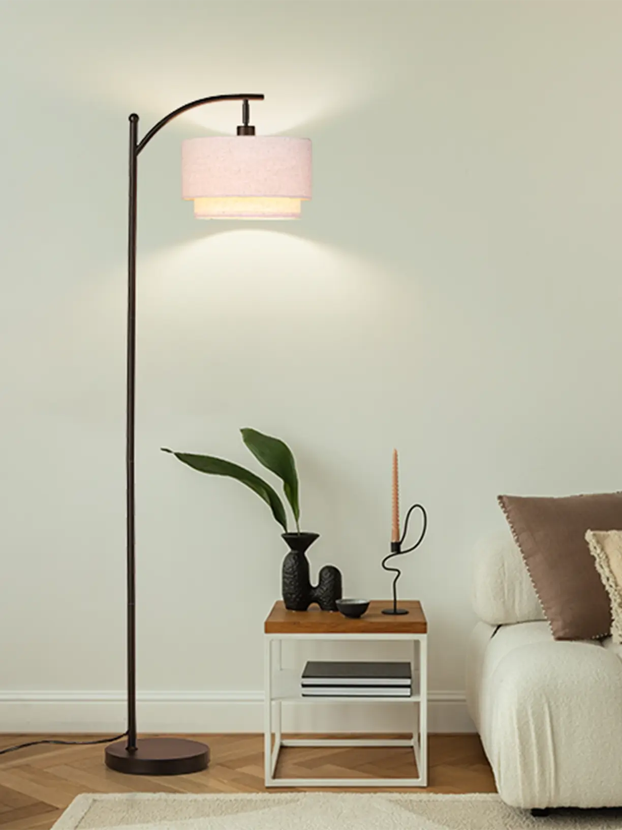 A sleek black mid-century modern arc floor lamp with a wide, flat circular shade, providing overhead illumination for a contemporary living room.